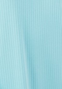 Tessuto a coste di un blu chiaro, con linee verticali equidistanti che mostrano texture e ombre morbide.
