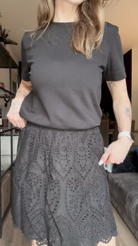 Top negro de manga corta combinado con una falda negra que presenta intrincados patrones recortados, una superficie texturizada y un dobladillo con forma ondulada.