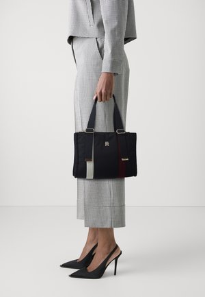 Granatowa torba na ramię wykonana z pikowanej tkaniny, z pionowymi paskami w kolorze szarym i bordowym, wyposażona w dwa solidne uchwyty do noszenia oraz złote elementy dekoracyjne.