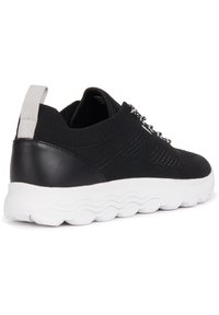 Czarny sportowy but z teksturowaną plecionką, skórzanym piętkiem i białą falistą podeszwą. Posiada pętelkę u góry i srebrne detale w sznurowaniu.