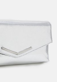 Silver metallic clutch wallet with a textured finish, featuring a V-shaped accent in chrome at the front and an envelope-style flap closure.