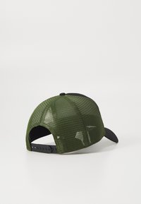 Gorra de malla verde con visera y parte trasera negras, que cuenta con un cierre ajustable a presión y un patrón texturizado en los paneles de malla.