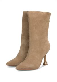 Bottes de cheville en suede beige avec un bout pointu, un talon aiguille haut et des détails de couture minimalistes. Présente un accent métallique sur le talon.
