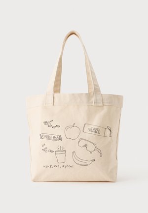 Sac cabas beige avec dessins au trait noirs d'objets de randonnée et texte "Hike, eat, repeat,", comprenant une pomme, une banane, une tasse de café, une barre énergétique et des lunettes de soleil.