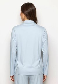 Maglietta azzurra chiara a maniche lunghe con colletto alla Coreana, tessuto morbido e vestibilità rilassata, caratterizzata da una finitura liscia e un design minimalista.