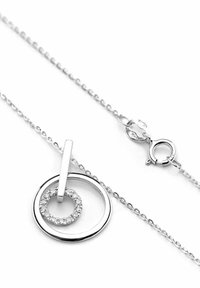 Sudraba kaklarota ar apaļu kulonu, kuram ir mazāks aplis ar caurspīdīgiem akmeņiem, piekarināts pie smalka ķēdītes ar aizdari.