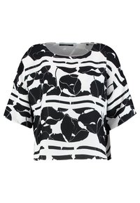 Blouse raccourcie en noir et blanc avec un motif floral et des rayures horizontales. Tissu doux et lisse avec une silhouette ample et des manches courtes.