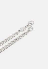 Silver chain bracelet with alternating oval and rounded links, featuring a lobster clasp and a hexagonal charm with a clear gemstone accent.