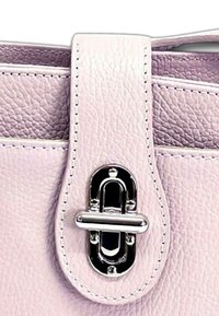 Lichtroze leren handtasriem met een gestructureerde afwerking, voorzien van een zilveren metalen sluiting en contrasterende witte stiksels langs de randen.