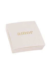 Scatola quadrata per gioielli di un pallido beige con una superficie liscia. La parola "amor" è impressa in oro sul coperchio. Design sobrio, finitura elegante.