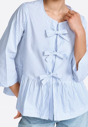 Jasnoniebieska i biała bluzka w paski z okrągłym dekoltem, trzema kokardami z przodu, rękawami do łokcia oraz dołem z falbanką.