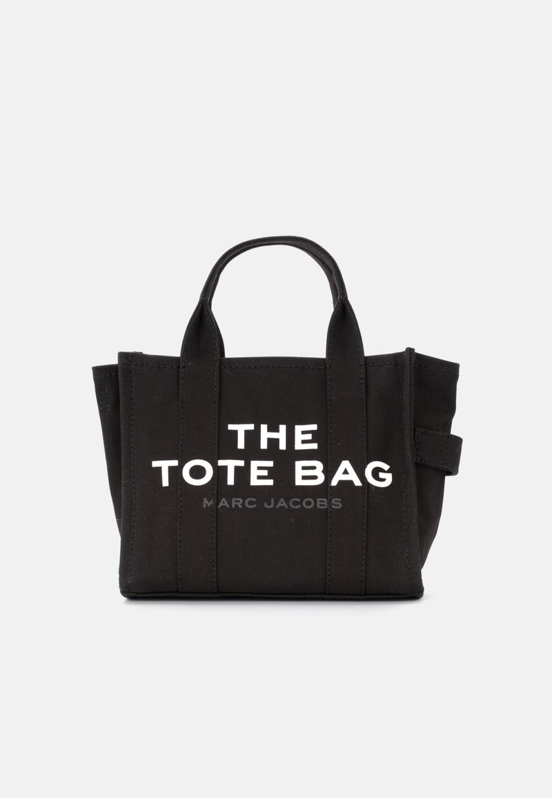 Sort canvas totebag med korte håndtag, trykt hvid tekst "THE TOTE BAG" og "MARC JACOBS" på fronten, struktureret design med sidelæg.
