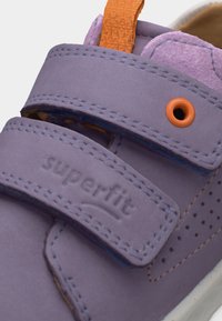 Μωβ παιδικό παπούτσι με δύο λουράκια βέλκρο, πορτοκαλί τράβηγμα και πορτοκαλί λεπτομέρεια με οπές στο πλάι.