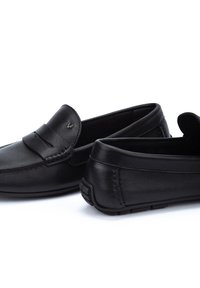 Mocasines de cuero negro con un acabado suave, que presentan una correa decorativa, costuras sutiles y una suela de goma texturizada para mayor agarre.