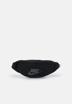 Sac banane Nike noir avec fermeture éclair et logo réfléchissant à l'avant, conçu pour un port mains libres.