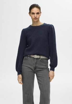 Navy blue knit sweater with long puff sleeves, crew neckline, and a soft texture, paired with gray high-waisted jeans and a light belt.