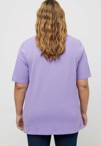 Lazurowy t-shirt z krótkim rękawem, wykonany z miękkiego materiału, o luźnym kroju, okrągłym dekolcie i prostym zakończeniu, w zestawie z ciemnoniebieskimi jeansami.