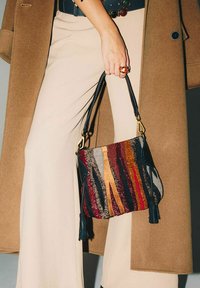 Piccola borsa a motivo con strisce multicolori in rosso, arancione e nero. Presenta una tracolla nera e dettagli con nappine. Superficie strutturata.