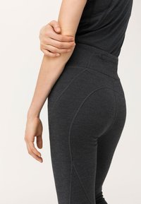 Leggings taille haute, gris foncé, fabriqués à partir d'un tissu texturé, avec des détails de couture le long des côtés pour une silhouette ajustée.