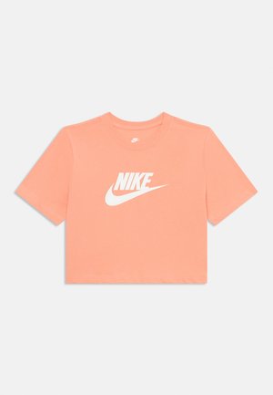 T-shirt court de couleur corail clair, en coton. Présente un logo Nike blanc centré sur le devant. Manches courtes et col rond.