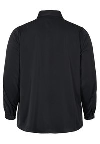 Chemise noire à manches longues, avec col, fabriquée en tissu lisse. Présente des poignets boutonnés et un ourlet droit, sans motifs ni logos visibles.