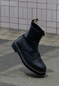 Μαύρα δερμάτινα μποτάκια αστραγάλου με πλαϊνό φερμουάρ, κίτρινη ραφή και υφή. Διαθέτουν ενισχυμένη μύτη και θηλιά έλξης.