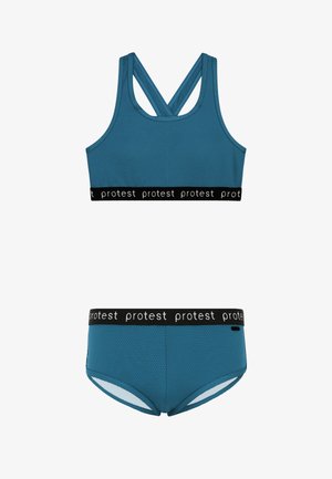 Plavi sportski grudnjak sa strukturiranom teksturom i ukriženim naramenicama, crni elastični pojas sa natpisom "protest." Usklađen plavi badić sličnog pasa.