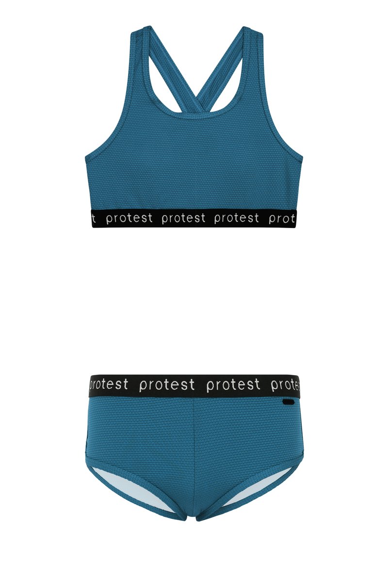 Sininen tekstuurinen urheilutoppi ristikkäisillä olkaimilla, musta joustava vyötärö, jossa on teksti "protesti". Yhteensopivat siniset bikinit, joissa on samanlainen vyötärö.