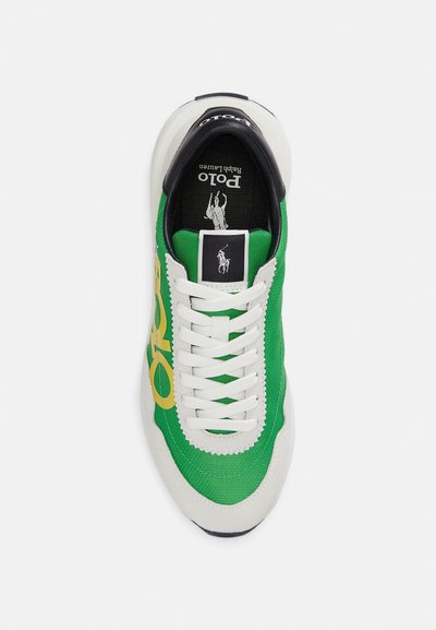 Πράσινο και λευκό αθλητικό παπούτσι με επάνω μέρος από υφασμάτινη υφή, με κίτρινο λογότυπο, μαύρη λεπτομέρεια στη φτέρνα και λευκά κορδόνια.