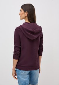 Bordowy hoodie z kieszenią kangurką, prążkowanymi mankietami i dołem. Wykonany z miękkiego materiału, o luźnym kroju z kapturem ze sznurkiem.