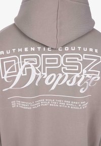 Mikina nazad v tlmenom fialovom odtieni s bielym textom "AUTENTICKÁ MÓDA DRPSZ Dropsize" a motivačným citátom nižšie.