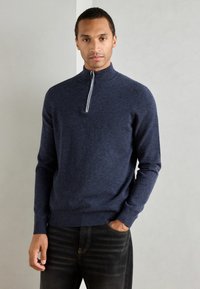 Navy blue knit pullover with a quarter-zip collar, featuring a contrasting white stripe along the zipper. Fitted sleeves and hem.