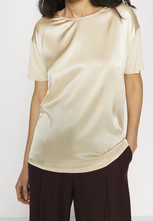 Haut en satin à manches courtes beige, avec un col arrondi et une coupe décontractée, doté d'une texture lisse et d'un léger éclat.