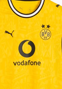 Κίτρινη φανέλα ποδοσφαίρου της Borussia Dortmund με μαύρο λογότυπο Puma, χορηγό Vodafone και το έμβλημα BVB 09 με δύο αστέρια πάνω από αυτό.
