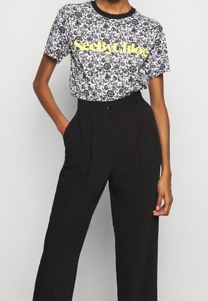 Person wearing black high-waist trousers and a white floral pattern T-shirt with "SeeByChloe" in yellow across the chest.