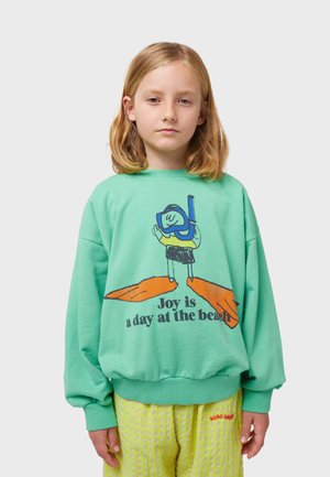 Felpa verde menta con vestibilità rilassata, dotata di una grafica di un subacqueo in stile cartone animato e testo stampato in nero. Tessuto morbido con polsini a coste.