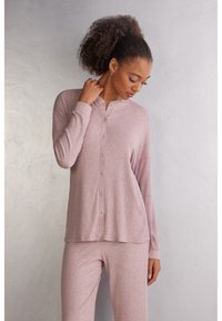 Světle růžový ribbed dlouhý rukáv top s mandarin límcem a zapínáním na knoflíky, spojený s odpovídajícími ribbed kalhotami, měkká textura a uvolněný střih.