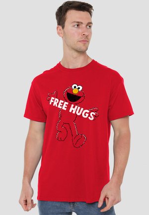 Red cotton t-shirt featuring a graphic of a cartoon character with the text "FREE HUGS" in bold white letters. Short sleeves and round neckline.