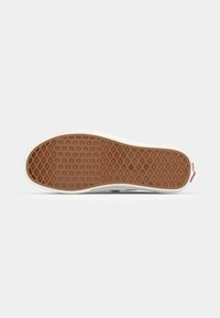 Rubber shoe sole featuring a diamond tread pattern, tan color with a white outer edge, and a subtle red accent near the heel.