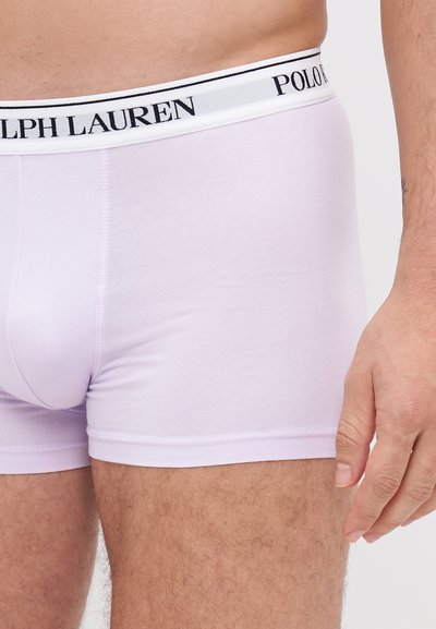 Boxers violets clairs avec une ceinture blanche portant le texte noir "RALPH LAUREN" et "POLO". Tissu doux, design ajusté, coutures minimales.