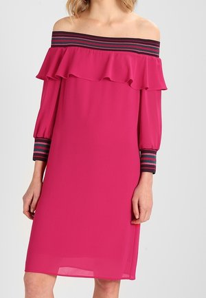 Robe fuchsia décolletée avec un col à volants, ornée de bandes marines et bordeaux sur les manches. Texture soyeuse, coupe droite.