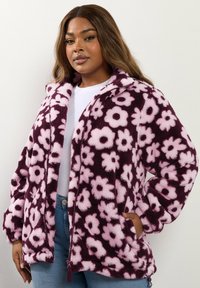 Fleece'owa kurtka w kolorze burgundowym z różowym kwiatowym wzorem, zapinana na zamek z przodu, z wysokim kołnierzem i kieszeniami po bokach; faktura o miękkim wyglądzie.