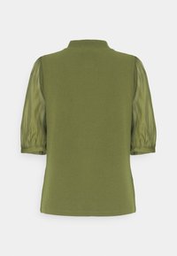 Oliivinvihreä toppi, jossa on yhtenäinen yläosa, läpikuultavat pökerryttävät hihat, kaulus ja suora helma. Sileä pinta ja kevyt materiaali.