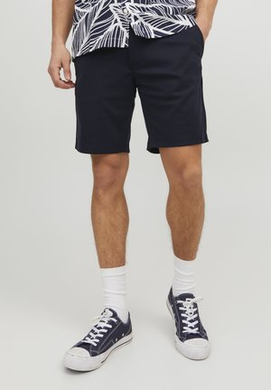 Granatowe szorty wykonane z mieszanki bawełny, o prostym kroju i bocznymi kieszeniami, w połączeniu z białymi skarpetkami i ciemnymi sneakersami.