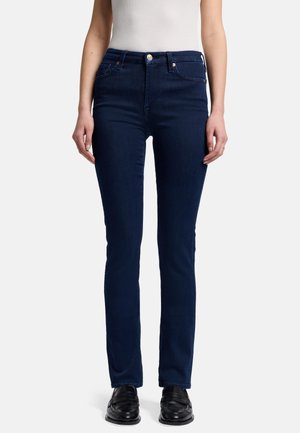 Un jean en denim bleu foncé avec une coupe slim, comportant des poches avant et arrière standard, une fermeture à bouton et des détails de couture minimaux.