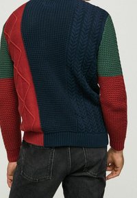 Maglione a maglia con design color block, composto da sezioni blu navy, rosse e verdi. Motivi testurizzati sulle maniche. Polsini e orlo a coste.