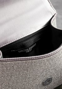 Grå clutch-taske med glat stofinteriør, sølvnitte-detaljer på ydersiden og en lynlåslomme synlig indeni.