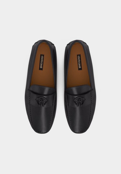 Μαύρα δερμάτινα μοκασίνια με ανάγλυφο λογότυπο στην κορυφή και μαύρη εσωτερική επένδυση, με την ετικέτα "roberto cavalli", εμφανιζόμενα από πάνω.