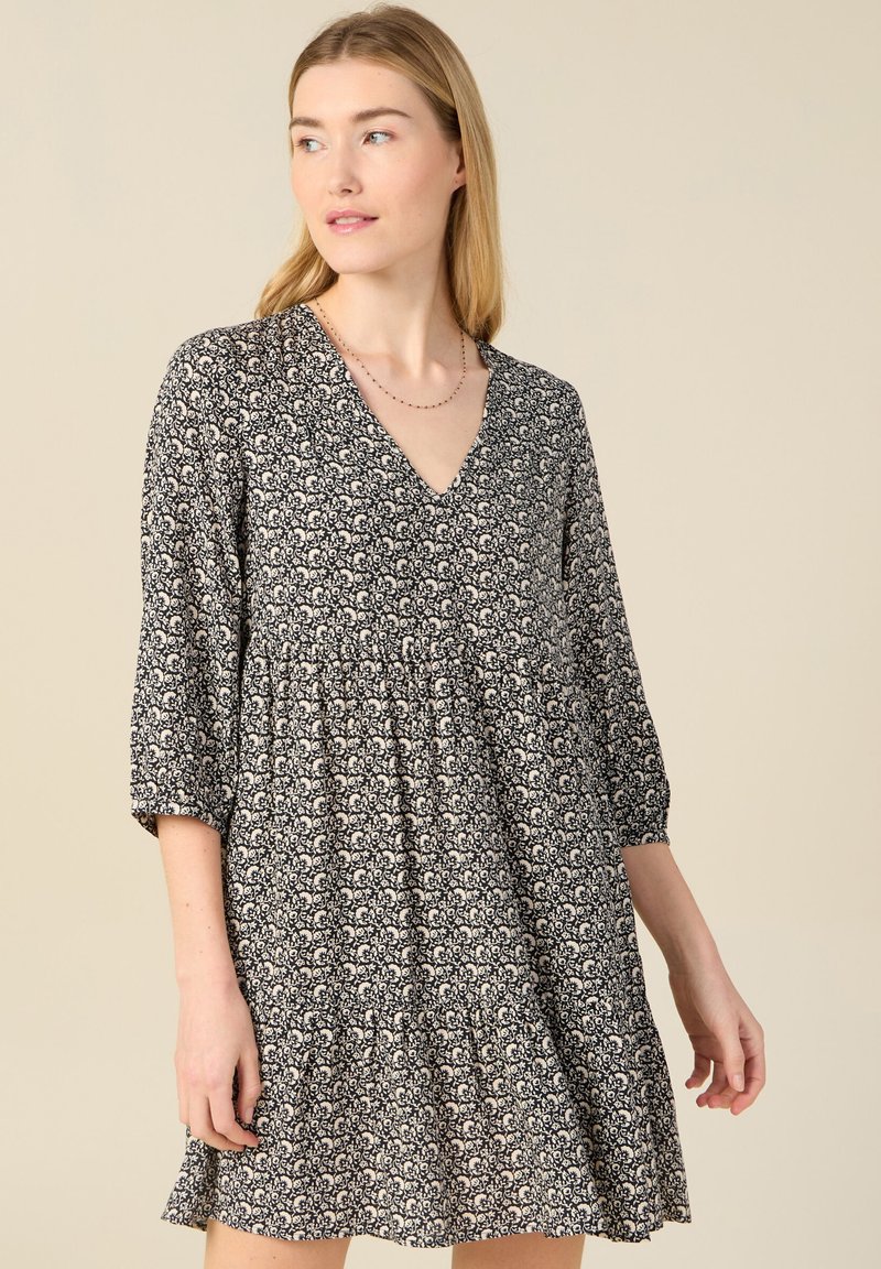 Vestido de estampado floral en blanco y negro con escote en V, mangas de tres cuartos y cintura fruncida, que presenta un dobladillo con volantes en capas.