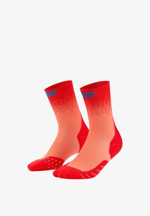 Paar rote und korallenfarbene Sportsocken mit Farbverlauf, blauer Beschriftung am Bündchen und strukturierten Sohlen, auf weißem Hintergrund aufrecht dargestellt.